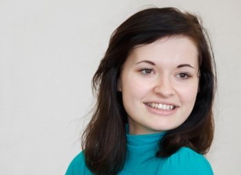 close-up portrait of a beautiful happy young cheerful brunette smiling girl in the blue sweater