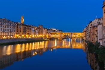 River Arno and famous bridge Ponte Vecchio at night, Arnolfo tower of Palazzo Vecchio in the background, Florence, Tuscany, Italy
