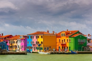 Colorful houses and boats on the famous island Burano, view from the sea, Venice, Italy