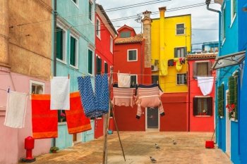 Patio with colorful houses with laundry drying on a rope on the famous island Burano, Venice, Italy