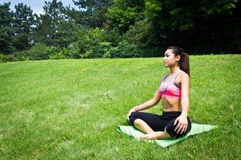 Young fit woman practices yoga in the park to meditate and relax