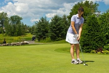 Woman golfer putting the golf ball on the green