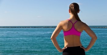 Woman in sports bra looking at the ocean