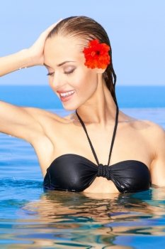 Woman with red flower posing in swimming pool