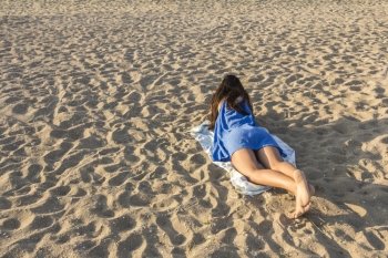 Rear view of pretty girl lying on sandy beach on hot summer 
