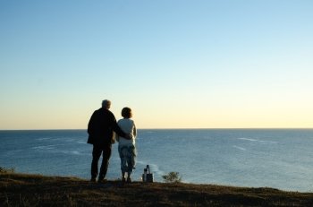 Couple watching the horizon at a blue sea in the evening sun