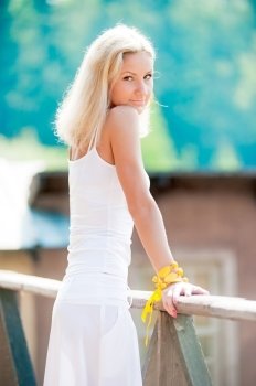 Young slim woman in white at the railing