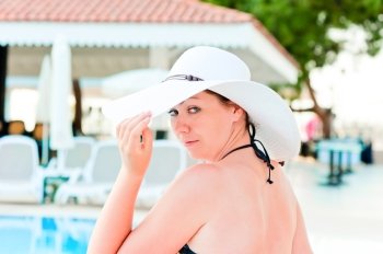 woman in a bikini holds the hand his hat