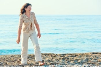 cheerful woman walking along the beach barefoot