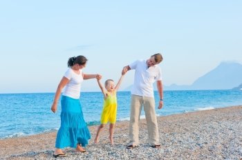 parents shake their little son on the beach