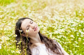 woman with closed eyes relaxes in daisies