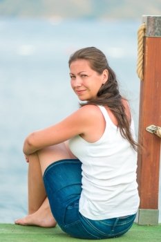 charming brunette resting sitting on a pier near the sea