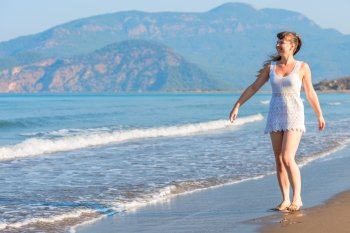 Happy girl walking barefoot on the beach