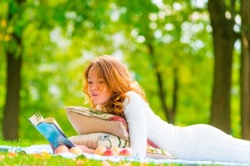 girl in white dress reading a book in the park