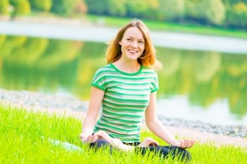 laughing cheerful girl in lotus position on the lake