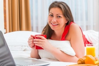 happy woman with a cup of hot coffee in the morning in bed
