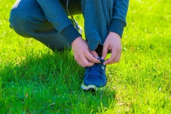 man in a sports suit to tie his shoes on the lawn