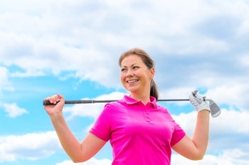 Happy portrait of a woman golfer with golf club against the sky