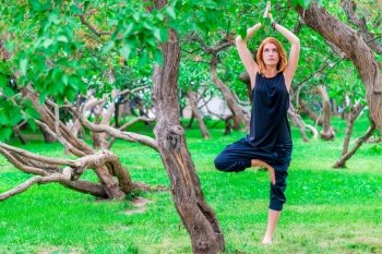 barefoot woman practices yoga in the park among the trees