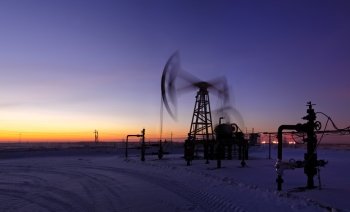 Pumpjack on the sunset sky background. Long exposure. Panorama.