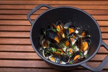 hot mussels with sauce in coast iron on wooden boards