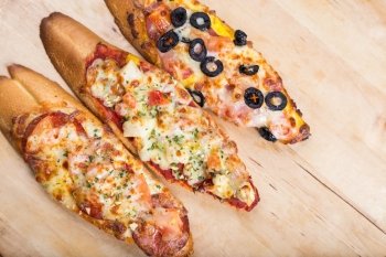 assorti bruscjetta with sausage, cheese, tomato fron big white baguette on wooden background