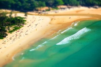 Tropical sandy beach landscape from high view point tilt shift effect. Beautiful turquoise ocean and people relaxing in waives. Rawai, Ya Nui beach, Phuket, Thailand
