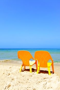 Two empty yellow chairs on beach close up