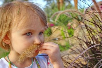 Little lady summer day mustache grass on the face