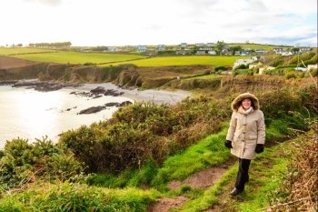 Irish landscape. Coastline atlantic ocean coast scenery cloudy blue sky, Church Bay County Cork, Ireland Europe. Woman female tourist walking