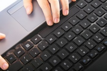 Cropped image of boy's schoolboy's hand typing on laptop keyboard