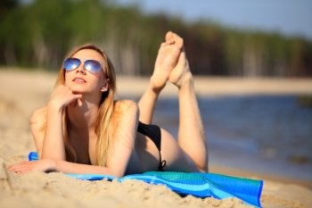 Smiling beautiful woman sunbathing on a beach. Summer and vacation
