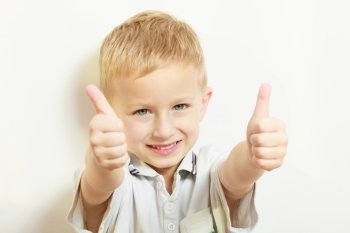Happy childhood. Portrait of smiling blond boy child kid preschooler showing thumb up success hand sign gesture. Indoor.