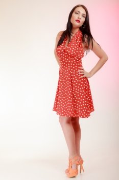 Vintage pinup style. Full length of beautiful stylized young woman. Attractive brunette girl in retro spotted red dress on pink. Disguise. Studio shot.