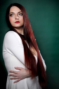 Young woman straight long dark hair make up posing in studio fashion photo green background