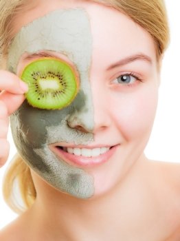 Skin care. Woman in clay mud mask on face covering eye with slice of kiwi. Girl taking care of dry complexion. Beauty treatment.