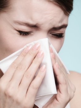 Flu cold or allergy symptom. Sick woman girl sneezing in tissue on blue. Health care.
