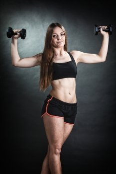 Fitness girl fit woman lifting dumbbells weights doing exercise with dumb bells training shoulder muscles gray background