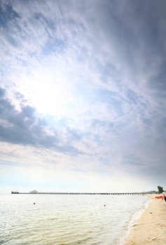 fluffy clouds blue sky above a surface of the sea and pier, Poland Baltic
