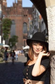 Portrait pretty retro woman in black hat outdoors on the street of the old town european city Gdansk Danzig