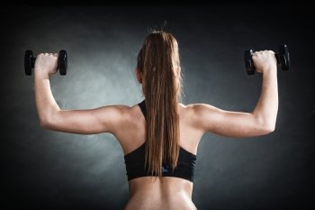 Fitness girl fit woman lifting dumbbells weights doing exercise with dumb bells training shoulder muscles back view gray background