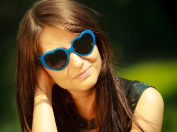 Summer vacation. Portrait of attractive brunette beautiful young woman in blue sunglasses in the shape of heart outdoor.