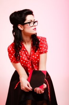 Retro. Portrait of stylish woman student or teacher in eyeglasses with book on pink. Brunette girl in pinup style. Education.