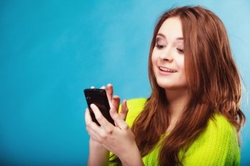 Technology and communication. Happy woman teenage girl texting on mobile phone, using smartphone reading sms message on blue