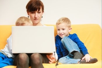 Happy family. Mother young woman and boys kids children sons using laptop computer sitting on sofa. Relax and technology at home.