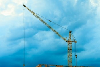 Construction site building hoisting crane on evening cloudy sky background