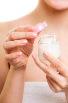Skincare. Closeup of woman holding lotion jar. Blond girl taking care of her dry complexion applying moisturizing cream isolated. Beauty treatment.