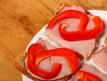 Healthy open faced sandwich with red paprika ham on wooden table background