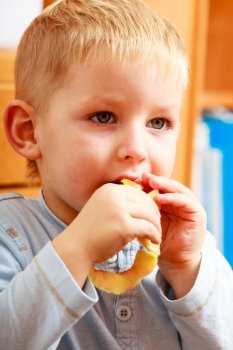 Portrait of cute blond child boy kid preschooler eating apple peel. Healthy diet and nutrition. At home.
