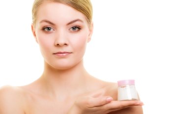 Skincare. Young woman holding cosmetic lotion jar. Blond girl taking care of her dry complexion applying moisturizing cream isolated. Beauty treatment.
